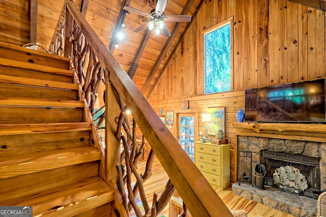 stairs with wood ceiling, beam ceiling, wood-type flooring, wooden walls, and a fireplace