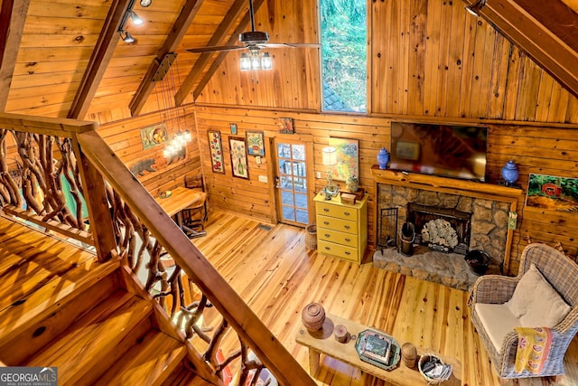 living room featuring wood walls, light hardwood / wood-style flooring, lofted ceiling with beams, wooden ceiling, and a fireplace