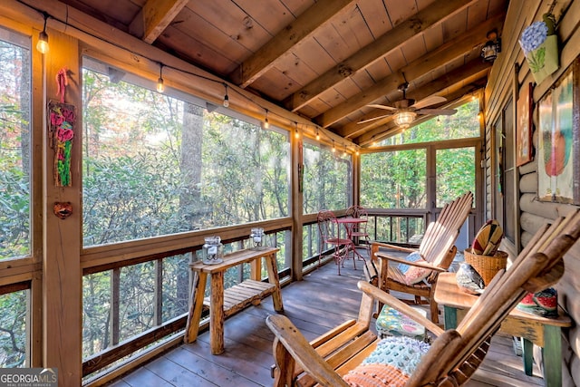 sunroom / solarium with ceiling fan, plenty of natural light, vaulted ceiling with beams, and wood ceiling