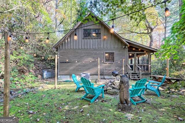 back of house with an outdoor fire pit, a yard, and a sunroom