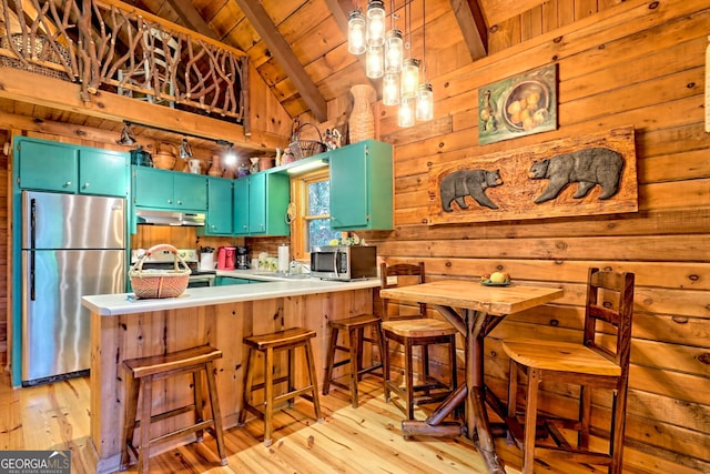 kitchen featuring wood walls, kitchen peninsula, stainless steel appliances, lofted ceiling with beams, and light hardwood / wood-style floors