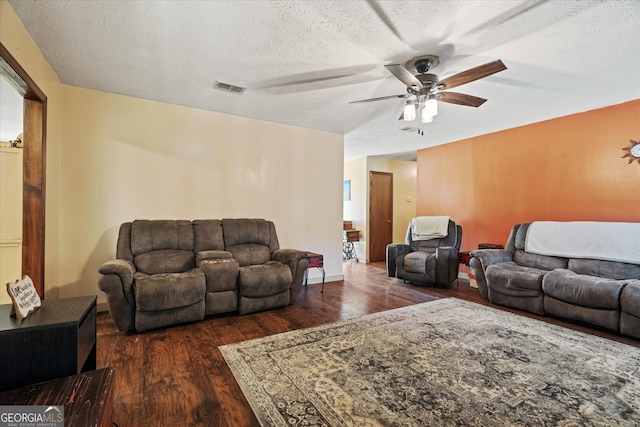 living room featuring ceiling fan, a textured ceiling, and dark wood-type flooring