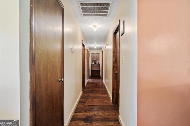 corridor with dark wood-type flooring and a textured ceiling