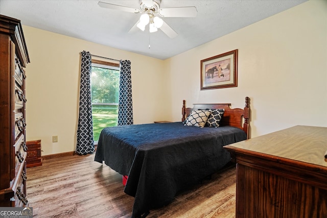 bedroom with ceiling fan, light hardwood / wood-style floors, and a textured ceiling