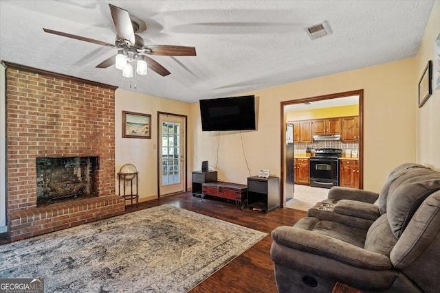 living room with ceiling fan, a textured ceiling, a fireplace, and dark hardwood / wood-style floors