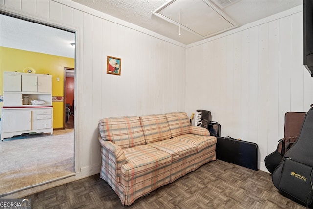 living room with wood walls, dark parquet flooring, and a textured ceiling