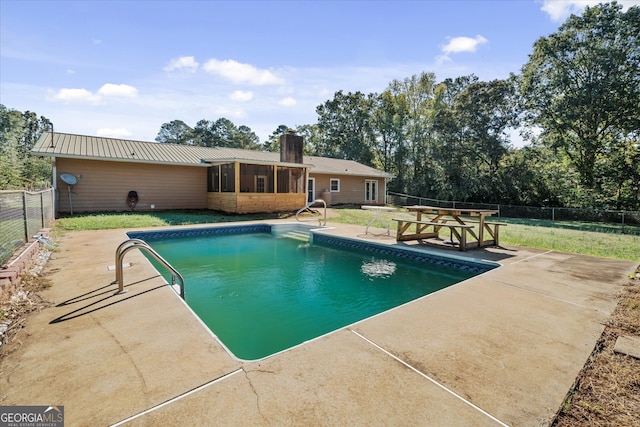 view of swimming pool featuring a sunroom and a patio area