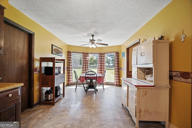 dining area featuring ceiling fan and a textured ceiling