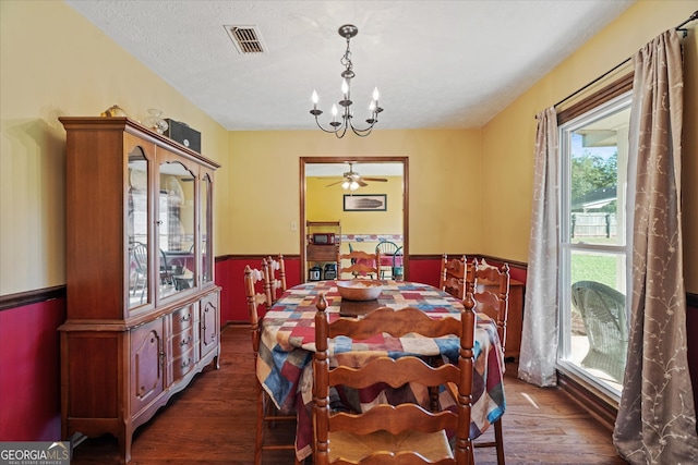 dining room with ceiling fan with notable chandelier, dark hardwood / wood-style flooring, and a textured ceiling