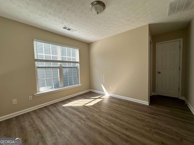 spare room with dark hardwood / wood-style flooring and a textured ceiling