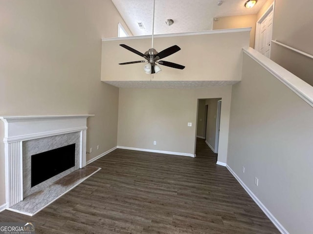 unfurnished living room with dark hardwood / wood-style floors, high vaulted ceiling, a high end fireplace, and ceiling fan