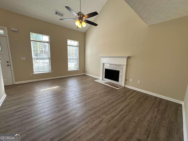 unfurnished living room featuring lofted ceiling, ceiling fan, dark wood-type flooring, a high end fireplace, and a textured ceiling