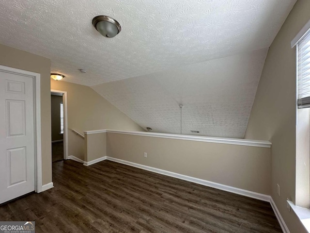 bonus room featuring a textured ceiling, dark hardwood / wood-style floors, and vaulted ceiling