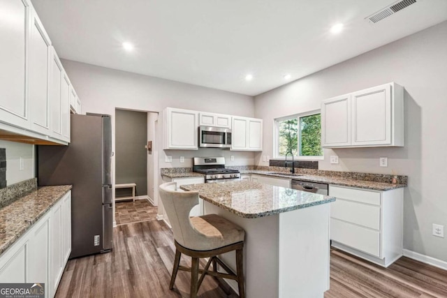 kitchen featuring sink, white cabinetry, stainless steel appliances, a center island, and hardwood / wood-style floors