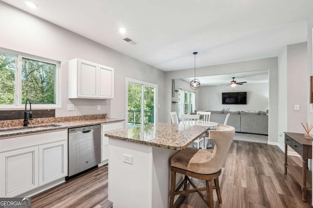 kitchen featuring plenty of natural light, hanging light fixtures, a kitchen island, and stainless steel dishwasher