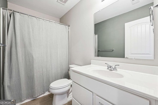 bathroom with walk in shower, hardwood / wood-style flooring, vanity, and toilet