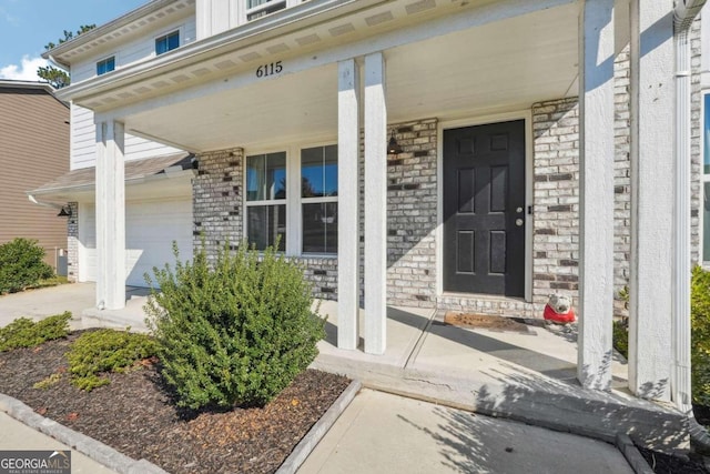 view of exterior entry featuring a garage and a porch