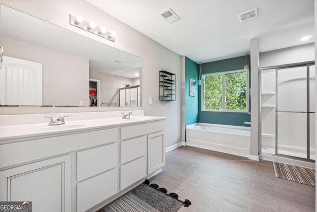 bathroom with hardwood / wood-style floors, vanity, and independent shower and bath