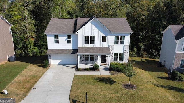 view of front of home with a garage, a front yard, and central AC