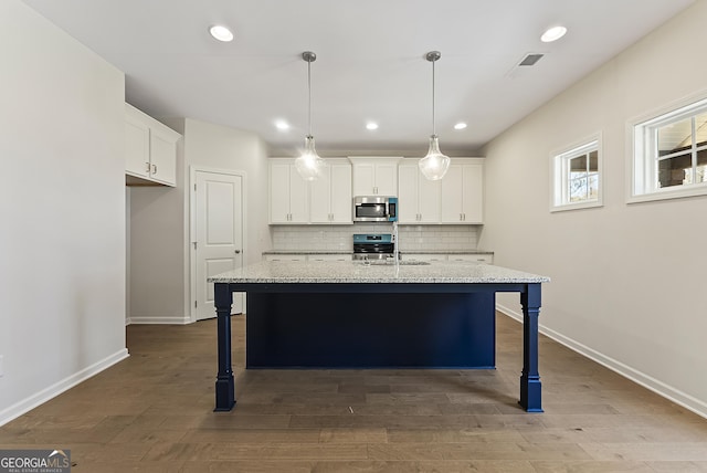 kitchen with white cabinets, light stone counters, and a kitchen island with sink