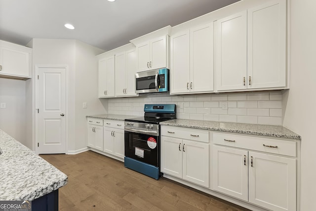 kitchen featuring white cabinets, light wood-type flooring, appliances with stainless steel finishes, and light stone countertops