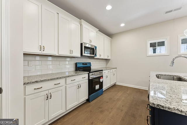 kitchen with white cabinetry, stainless steel appliances, light stone countertops, and sink