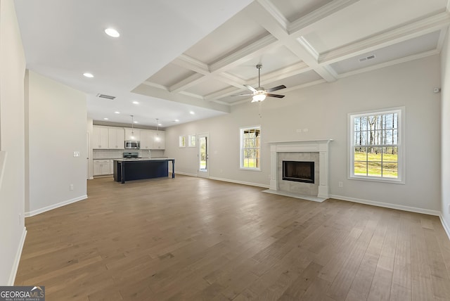 unfurnished living room featuring beamed ceiling, a premium fireplace, wood-type flooring, and coffered ceiling