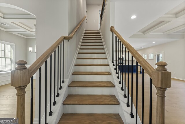 stairs featuring coffered ceiling, wood-type flooring, beamed ceiling, and ornamental molding