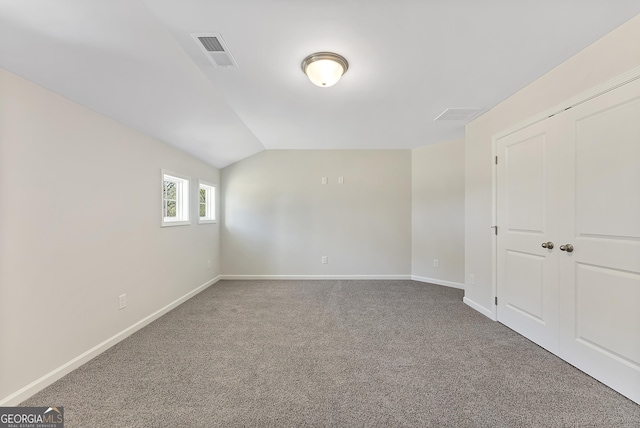 unfurnished bedroom with carpet floors, a closet, and vaulted ceiling