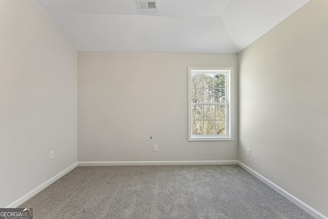 carpeted empty room featuring vaulted ceiling