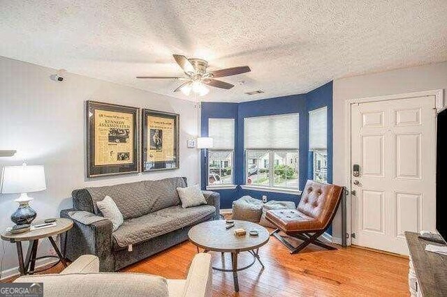 living room with wood-type flooring, a textured ceiling, and ceiling fan