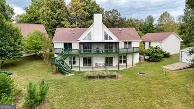 rear view of property featuring a wooden deck, a lawn, and a patio area