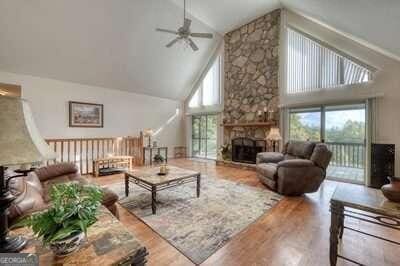 living room featuring ceiling fan, high vaulted ceiling, a fireplace, and hardwood / wood-style flooring