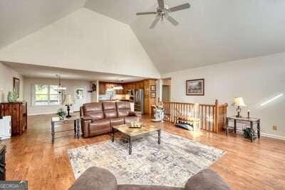 living room featuring high vaulted ceiling, ceiling fan, and wood-type flooring