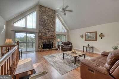 living room featuring high vaulted ceiling, a fireplace, ceiling fan, and light hardwood / wood-style floors