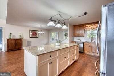 kitchen with appliances with stainless steel finishes, light stone countertops, hardwood / wood-style floors, and a center island