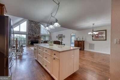 kitchen with a fireplace, stainless steel refrigerator, a center island, and wood-type flooring