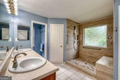 bathroom with an inviting chandelier, vanity, tile patterned floors, and tiled shower