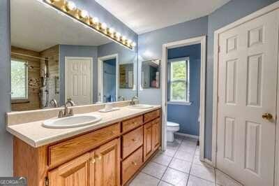 bathroom with walk in shower, vanity, toilet, and tile patterned floors