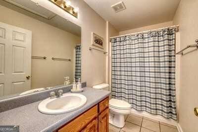 bathroom with vanity, tile patterned flooring, toilet, and curtained shower