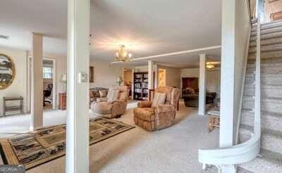 carpeted living room featuring an inviting chandelier and ornate columns