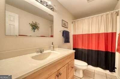 bathroom featuring tile patterned flooring, a shower with shower curtain, vanity, and toilet