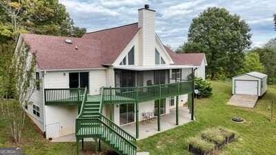 back of property featuring a shed, a yard, a patio, and a deck