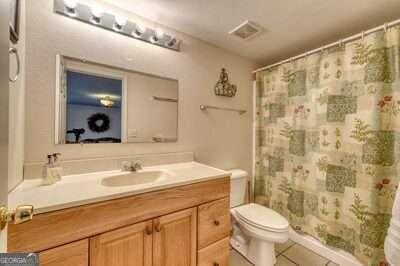 bathroom featuring tile patterned floors, toilet, walk in shower, and vanity