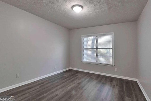 empty room with dark hardwood / wood-style floors and a textured ceiling