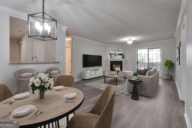 living room featuring wood-type flooring, ornamental molding, an inviting chandelier, and a textured ceiling