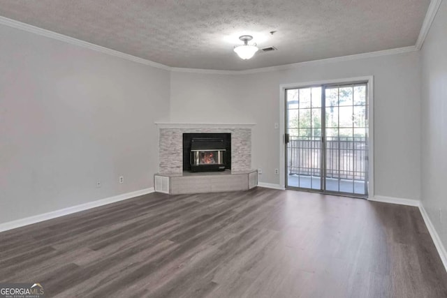 unfurnished living room featuring crown molding, dark wood-type flooring, a stone fireplace, and a textured ceiling