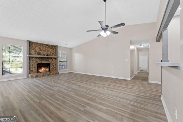 unfurnished living room featuring ceiling fan, light hardwood / wood-style flooring, a fireplace, and lofted ceiling