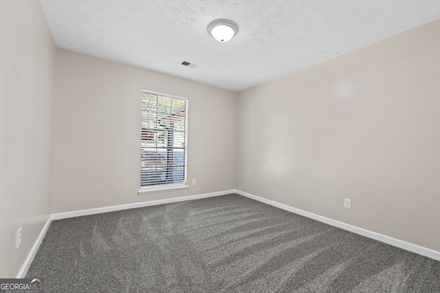 carpeted empty room with a textured ceiling, visible vents, and baseboards