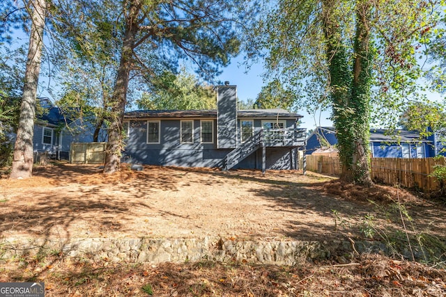 rear view of house with fence, a chimney, stairs, and a wooden deck